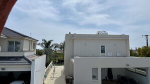 Un quartier résidentiel avec des bâtiments modernes, notamment une maison avec un garage et un bâtiment blanc doté d’un toit plat.