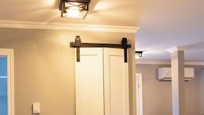 A hallway with a white door, a light fixture, and an air conditioning unit.