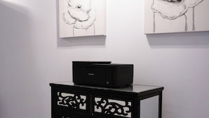 Een zwarte console tafel met gedetailleerde uitsparingen, geplaatst voor een witte muur met daarboven twee abstracte bloemschilderijen.