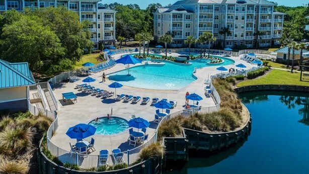 A resort with a large central pool surrounded by lounge areas and a smaller pool.