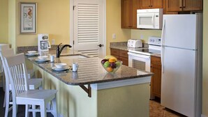 A compact kitchen with a central island, white cabinetry, a microwave, a toaster, and a refrigerator.