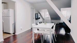 A modern kitchen with a white refrigerator, a stainless steel trash can, and a dining area with a white table and chairs.