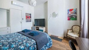 A hotel room with a bed, a TV, a chair, and a desk.