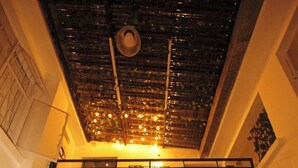 A dining area with wooden chairs, a table, and a ceiling with hanging lights. - Hotel El Encanto (Bogotá)