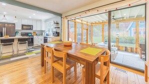 Una cocina moderna con armarios blancos, electrodomésticos de acero inoxidable y una mesa de comedor de madera con sillas.