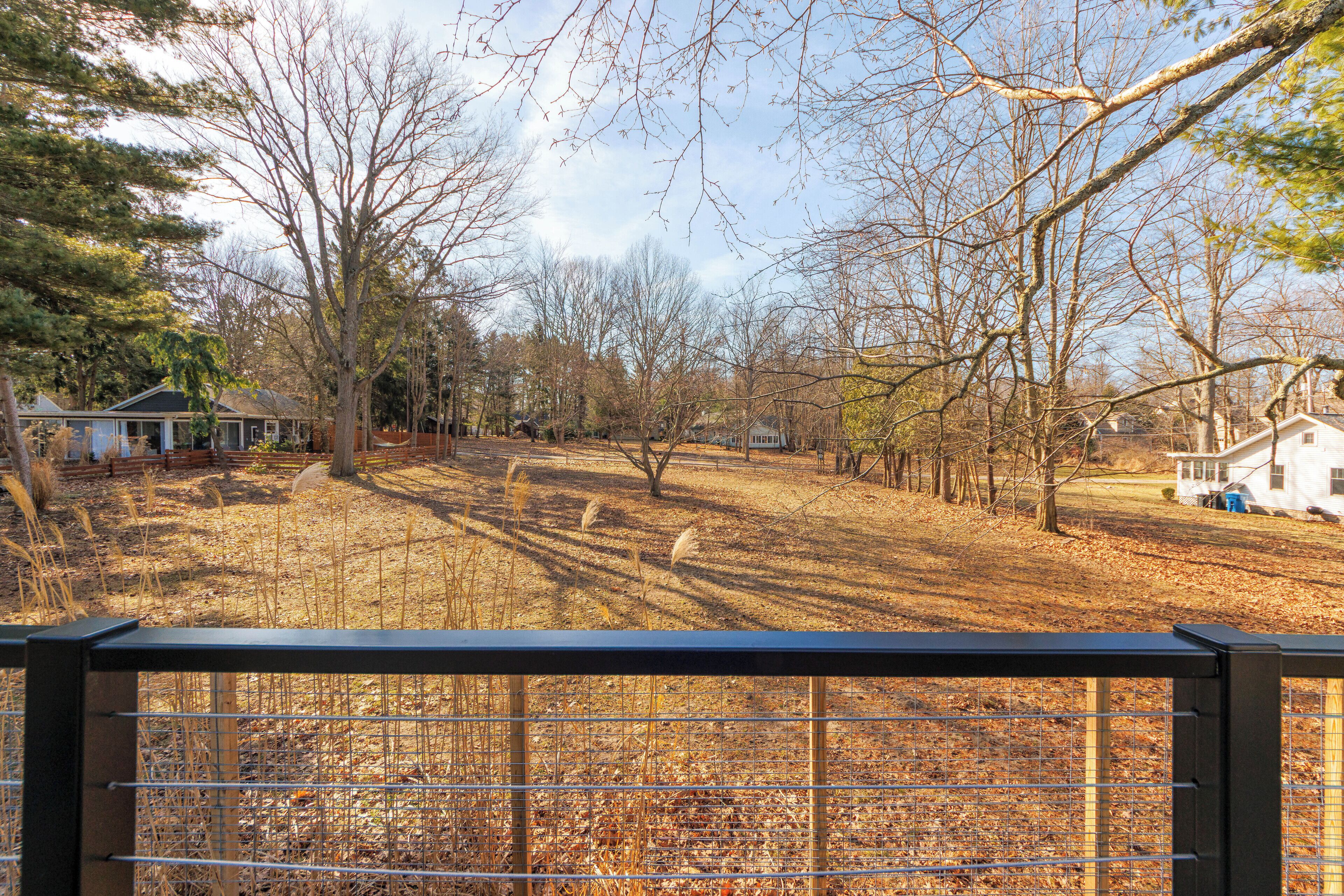 A fenced yard with leaf-covered ground, trees, and houses in the background.