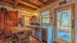 Eine rustikale Kücheneinrichtung im Chalet-Stil mit Holzbalken, einem Esstisch mit Stühlen, einer Spüle und einer Mikrowelle.
