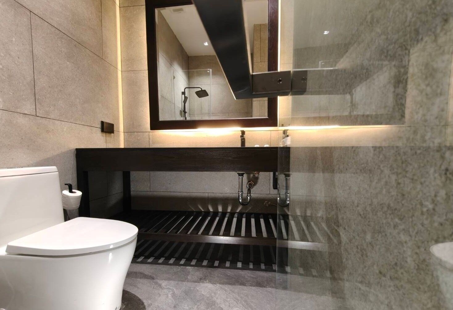 Een moderne badkamer met toilet, wastafel en douche.