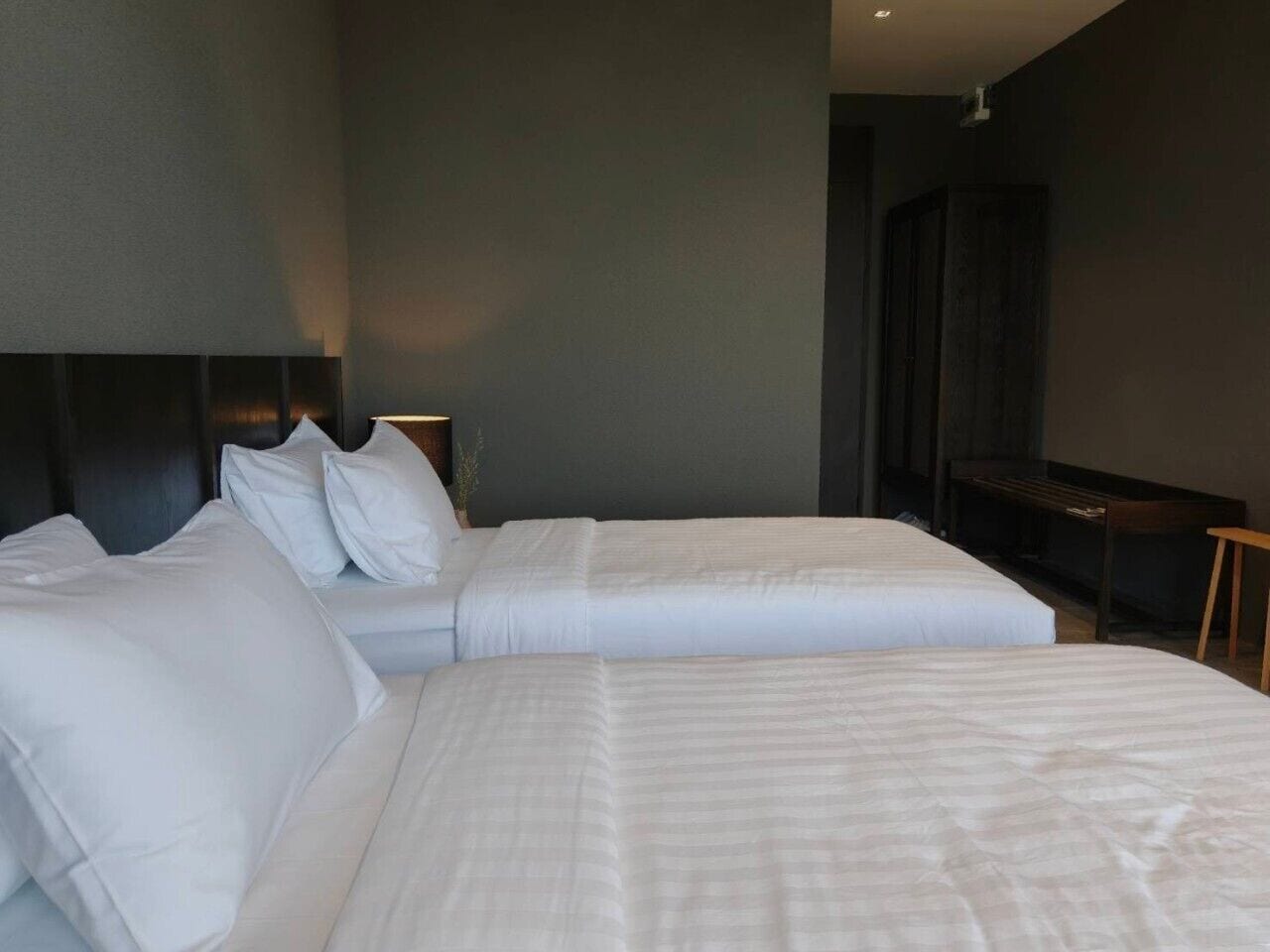 A hotel room with two beds, a dark headboard, a small table, and a TV.
