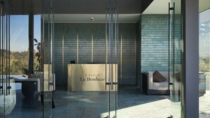 Een moderne hotel lobby met een receptiebalie met de tekst 'Le Bonheur'.