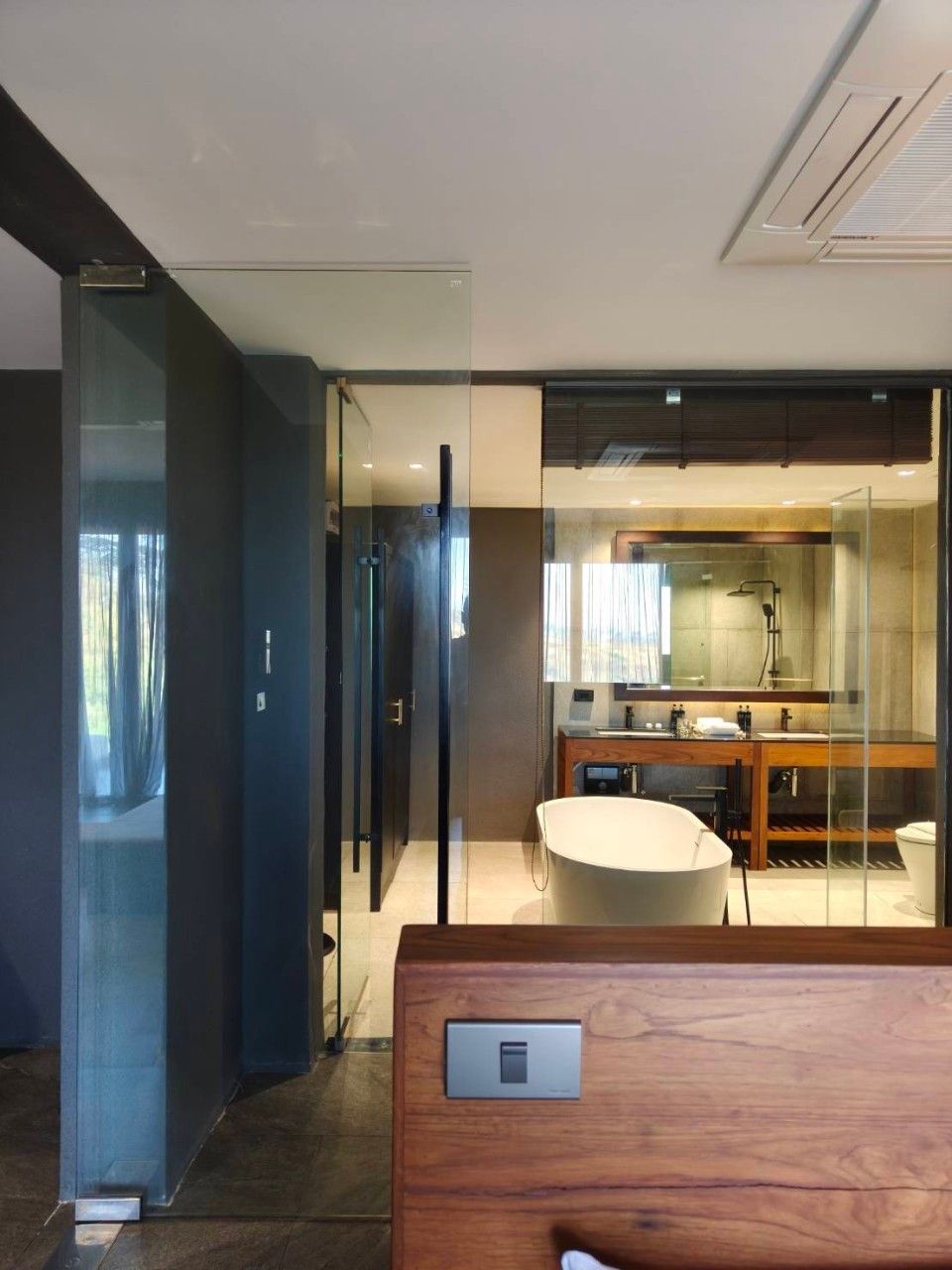 Een moderne badkamer met een douchecabine van glas, een houten wastafelmeubel en een ruime badkuip.