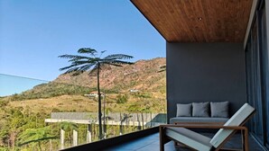 Een balkon met een moderne lounge fauteuil en een bank, met uitzicht op een glooiend landschap.