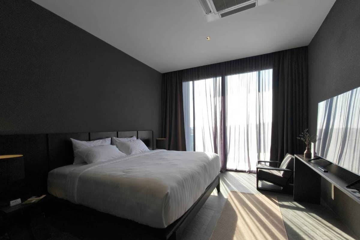 A modern hotel room with a large bed, a desk, and a television.