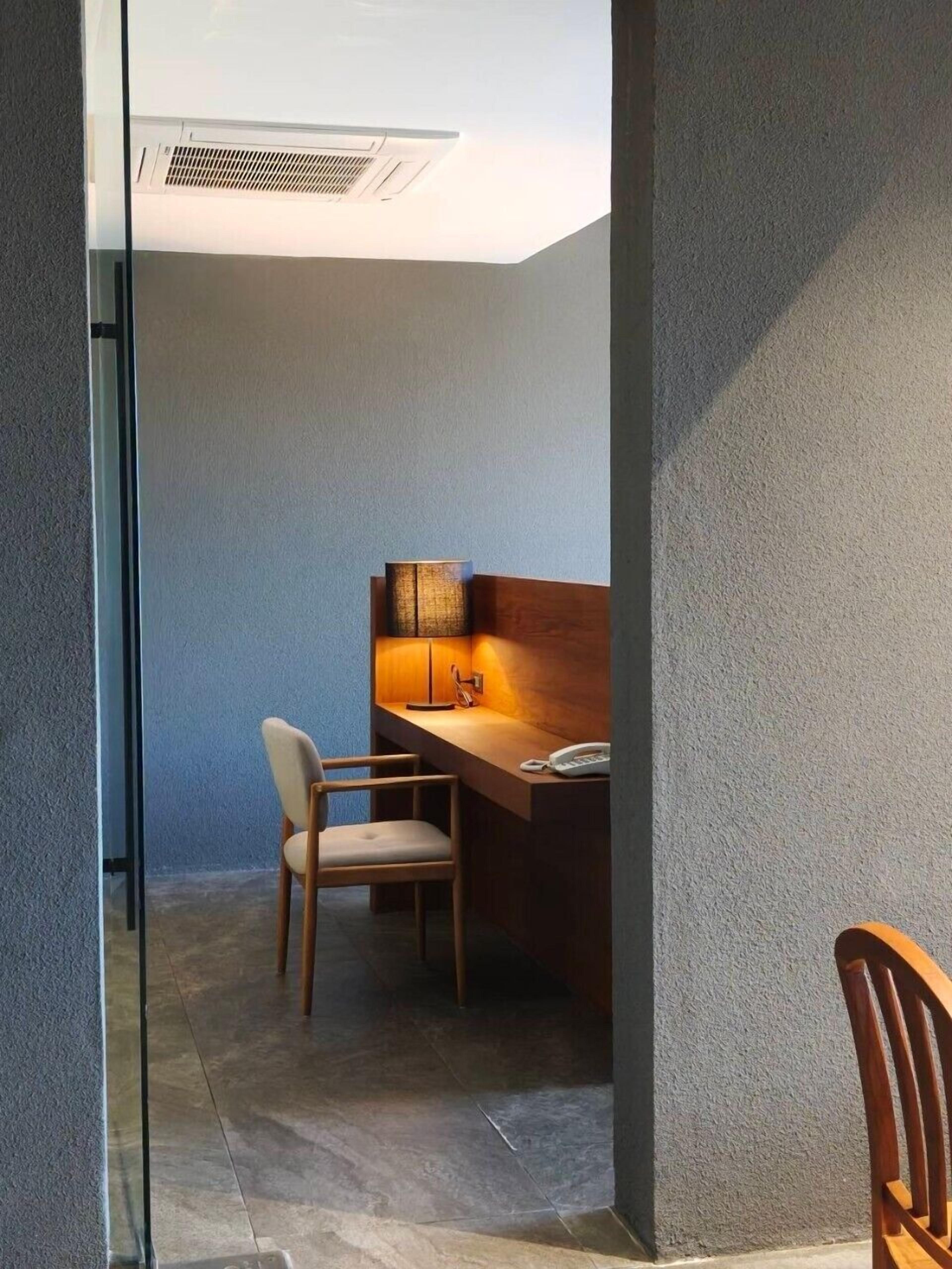 A modern room with a desk, chair, and a lamp.