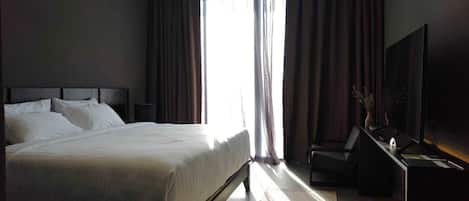 Een moderne hotelkamer met een groot bed, een bureau met een lamp en een televisie.