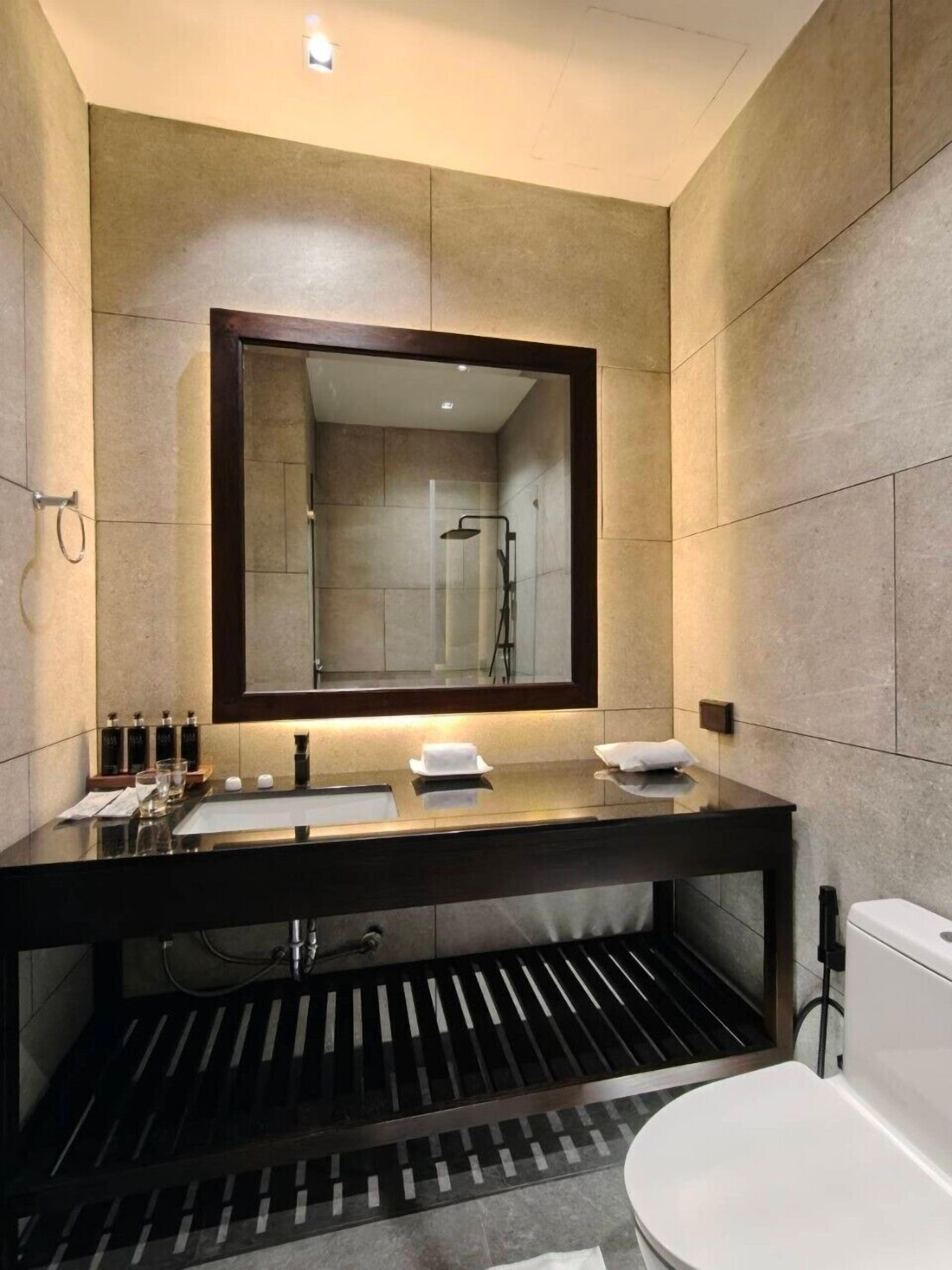 A modern bathroom with a large mirror, a black countertop, and a toilet.