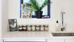 A kitchen with a potted plant, a cookbook, and jars of spices.