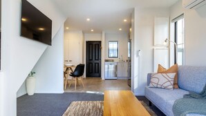 Una sala de estar moderna con un sofá, una mesa de centro y un televisor montado en la pared.