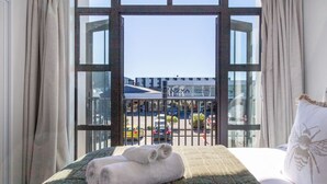 A hotel room with a large window, a bed with a green quilt, and a view of a building labeled "Christchurch Campus".