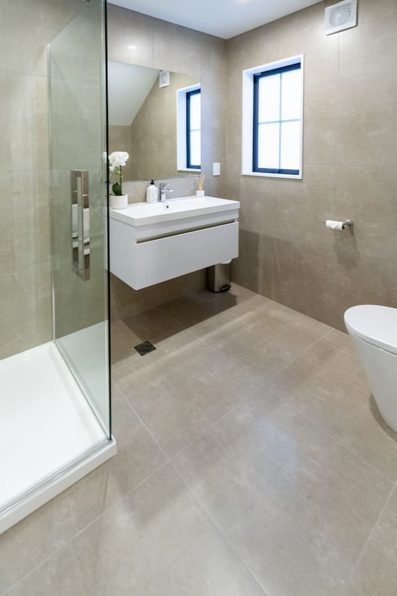 Une salle de bain moderne avec une douche à parois de verre, un lavabo blanc et des toilettes.