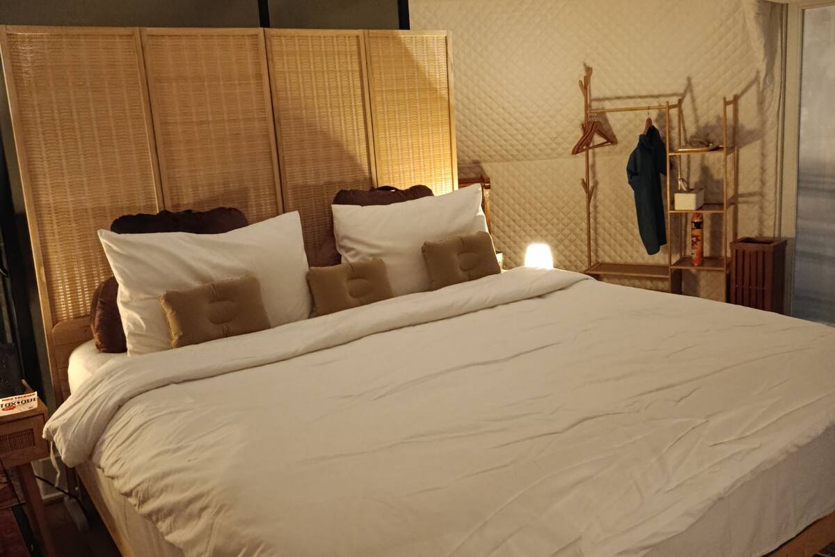 Ein Schlafzimmer mit einem großen Bett, einem hölzernen Kopfteil, einem Nachttisch und einem Kleiderschrank.