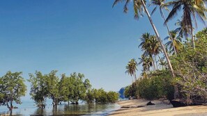 A beach with palm trees, clear water, and a distant mountain. - Krabi Campsite Glamping & Camping (Krabi)