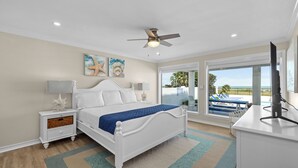 A bedroom with a bed, nightstand, and a view of a pool area. - Luxury Beachfront Home w/ private beach access & private heated pool! (South Padre Island)