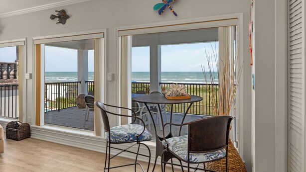 A balcony with a view of the ocean, wicker chairs, and a table with decorative items. - Luxury Beachfront Home w/ private beach access & private heated pool! (South Padre Island)