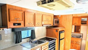 Una cucina funzionale con mobili in legno, un forno a microonde, un piano cottura e un lavandino.