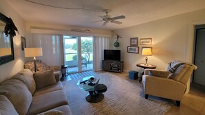 A living room with a sofa, armchairs, a coffee table, a TV, and a ceiling fan. - CP 413 Dune View Condo - Welcome To Paradise! (Fort Pierce)