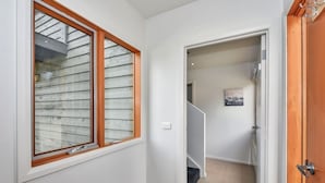 A hallway with a wooden door, a window with a wooden frame, and a staircase leading to another room. - The Chalet (Dinner Plain)