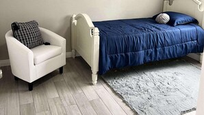 A bedroom with a bed, a white armchair, a grey rug, and a ceiling fan. - New ADU -  Charming 1-bedroom house with AC, WiFi in fabulous Bakersfield (Bakersfield)
