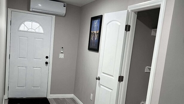 A hallway with a white door, a framed picture on the wall, and a white couch. - New ADU -  Charming 1-bedroom house with AC, WiFi in fabulous Bakersfield (Bakersfield)