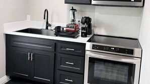 A modern kitchen with black cabinets, a microwave, a coffee maker, and an oven. - New ADU -  Charming 1-bedroom house with AC, WiFi in fabulous Bakersfield (Bakersfield)