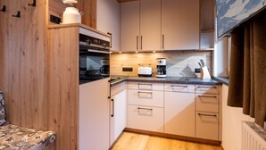 Eine kleine Küche mit Holzausstattung, einem Einbauofen, einer Kaffeemaschine und einem Toaster.