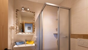 Ein modernes Badezimmer mit Duschkabine aus Glas, Waschbecken mit Spiegel darüber und Toilette.