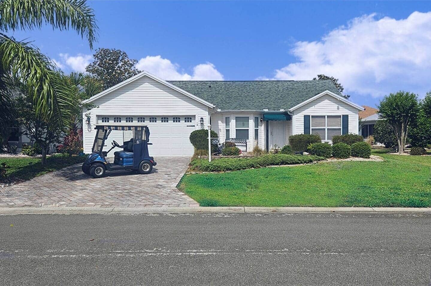 Une maison de plain-pied avec un garage, une allée et une pelouse.
