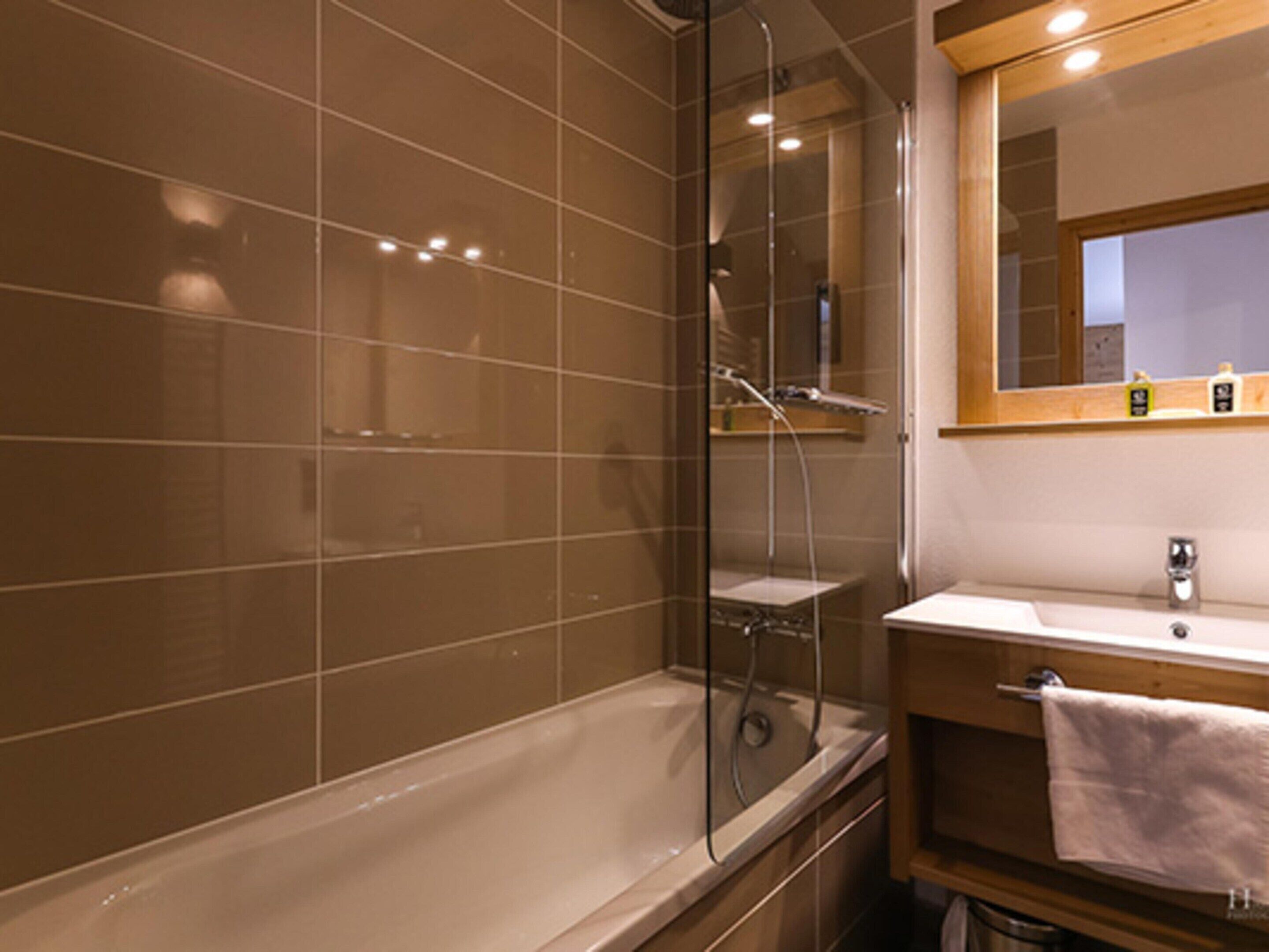 A bathroom with a bathtub, a glass-enclosed shower, and a vanity with a mirror.
