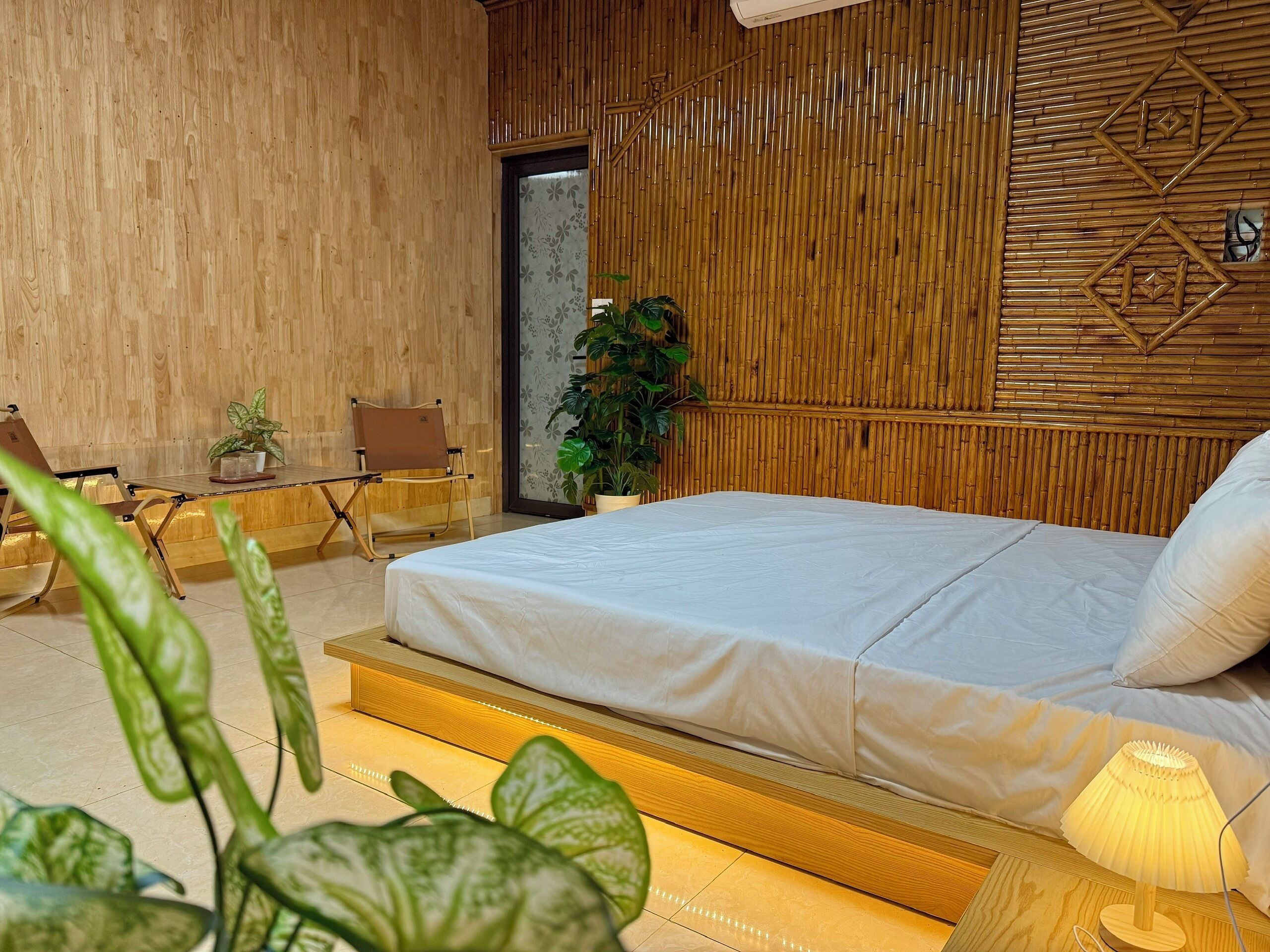 A modern bedroom with a wooden bed, a small table, a chair, and a potted plant.