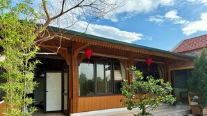 A traditional wooden building with a tiled roof, a staircase leading to the entrance, and a potted plant on the steps. - May Garden Homestay (Ninh Binh)