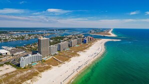 An aerial view of a coastal city with a long beach, high-rise buildings, and a clear blue sky. - The Osprey 12-Bayfront w/ boat slip, elevator, & pool. Sapphire Osprey by Kaiser (Orange Beach)