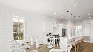 A modern kitchen with white cabinetry, wooden flooring, and a central island with seating. - The Osprey 12-Bayfront w/ boat slip, elevator, & pool. Sapphire Osprey by Kaiser (Orange Beach)