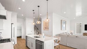 A modern kitchen with white cabinetry, a central island, and pendant lighting. - The Osprey 12-Bayfront w/ boat slip, elevator, & pool. Sapphire Osprey by Kaiser (Orange Beach)