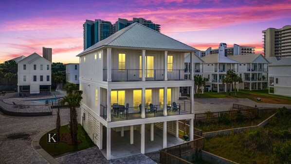 A two-story building with balconies, a pool, and a view of surrounding high-rise buildings.
