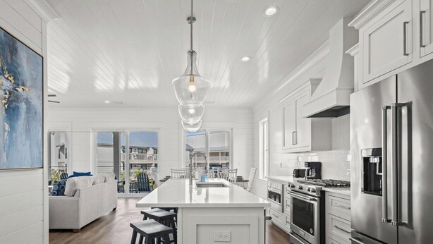 Una cocina moderna con una isla central, electrodomésticos de acero inoxidable y un amplio ventanal con vistas a un balcón.