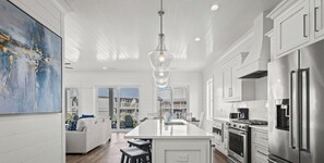 Cozinha moderna com ilha central, eletrodomésticos de aço inoxidável e uma grande janela com vista para uma varanda.