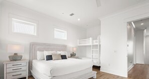 Une chambre à coucher avec un grand lit, des tables de chevet, un lit superposé et un dressing.
