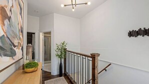 Ein modernes Interieur mit Holzboden, einer Treppe mit Metallgeländer und einem großen abstrakten Gemälde an der Wand.