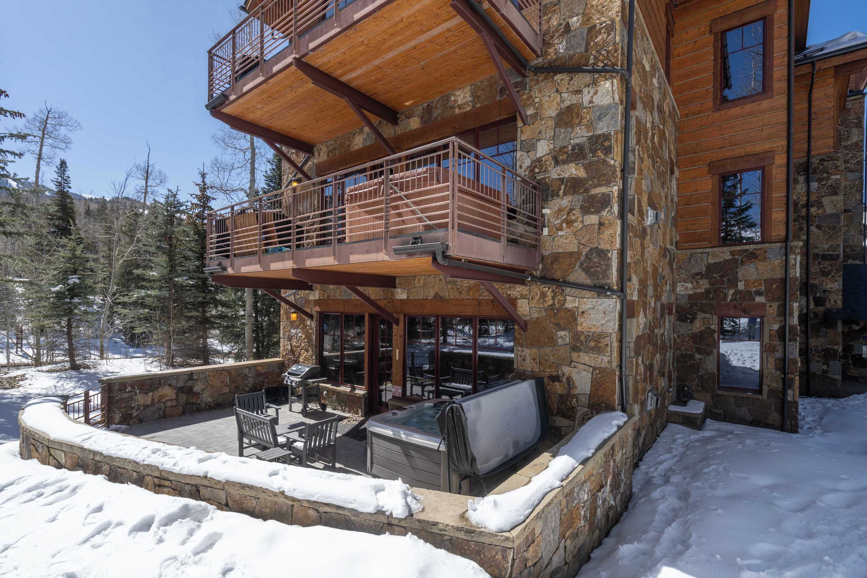 A multi-level stone building with a hot tub and outdoor seating area.