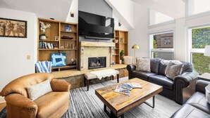 A modern living room with a fireplace, leather sofas, and a large TV.